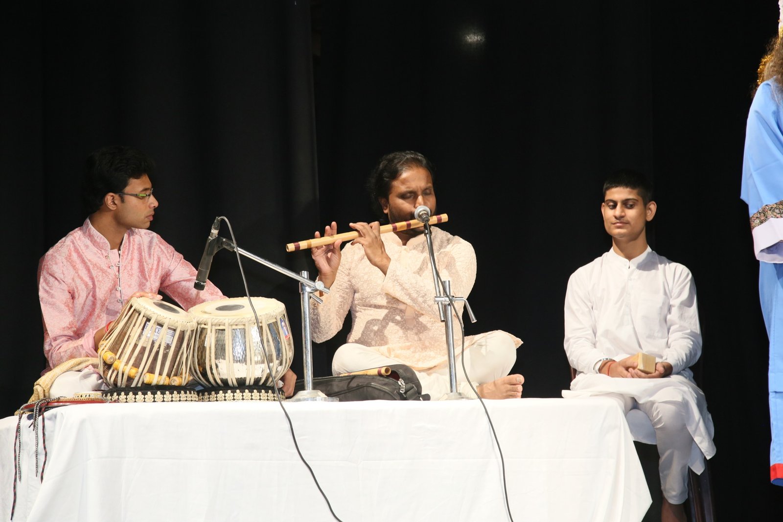 Tabla, flute and young accompanists on a theatre stage